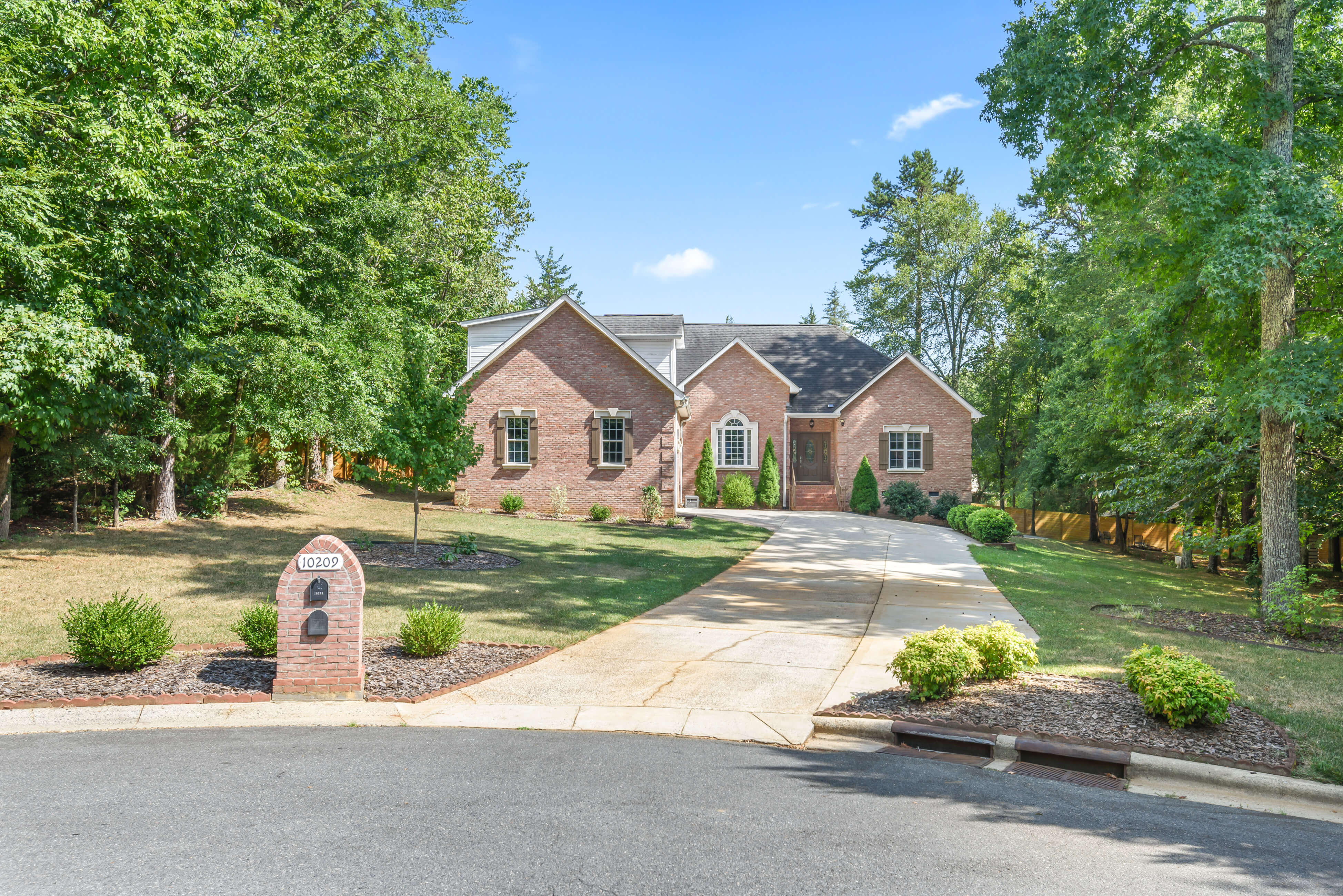 Front exterior of brick single-story home with gables, long curved driveway, and brick mailbox at 10209 Maple Haven Ct