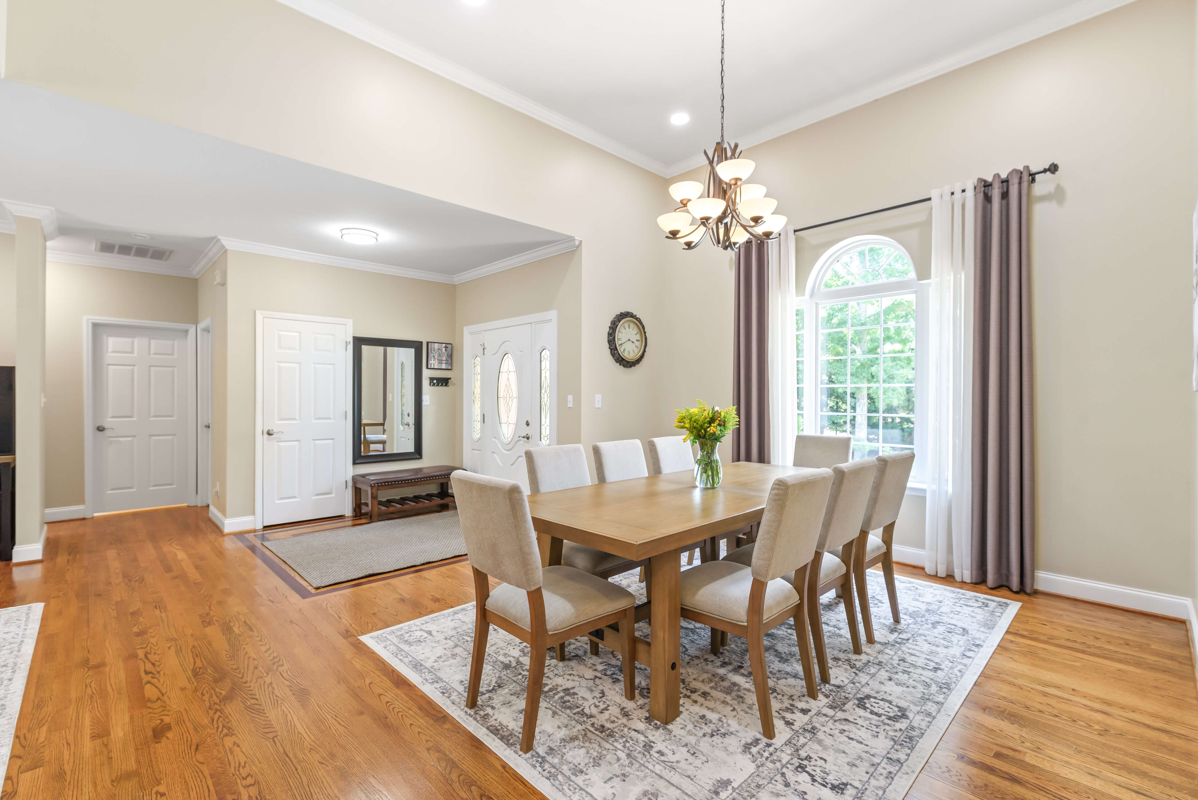 Dining room looking toward foyer—table for eight, chandelier, arched window, and hardwood floors