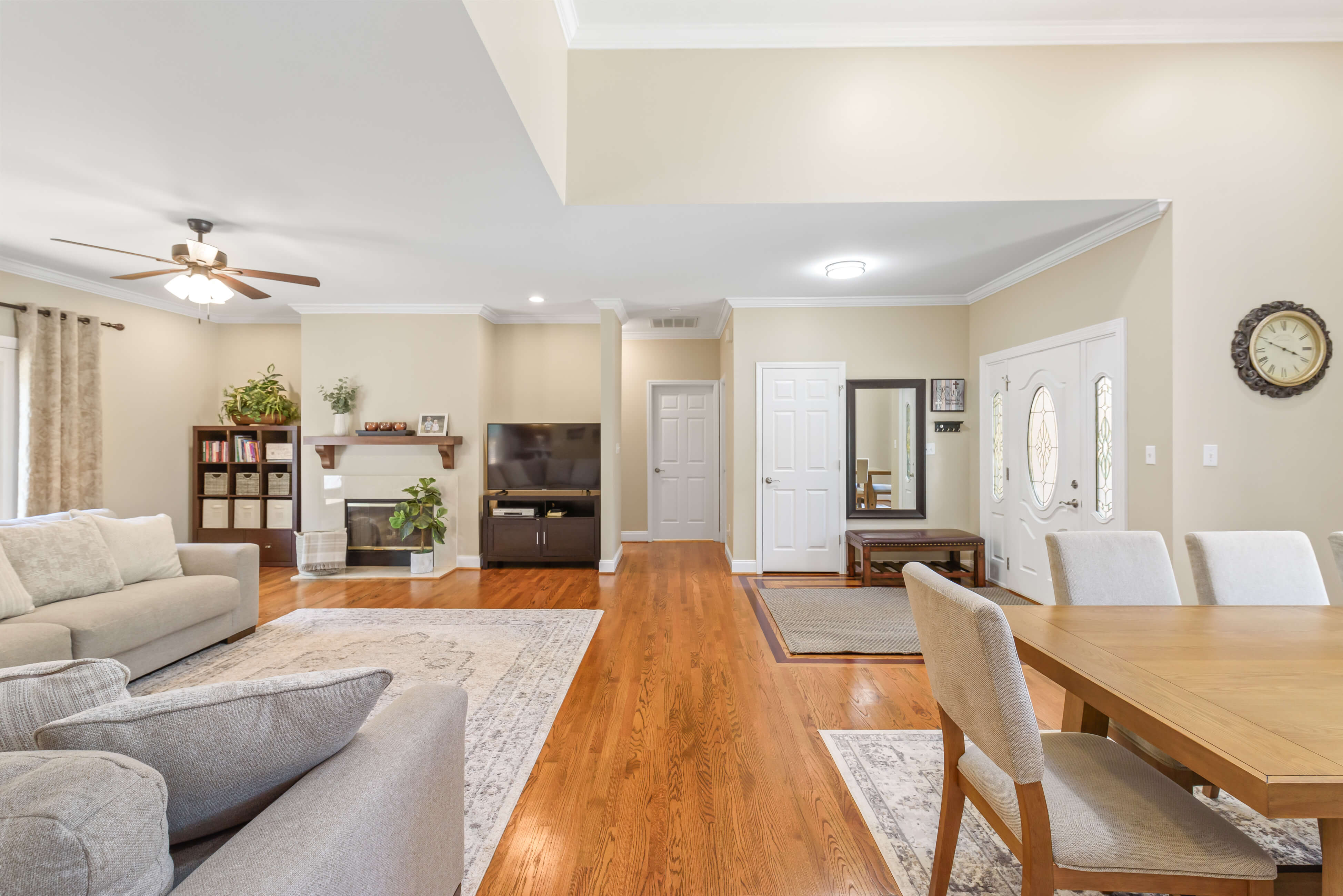 Open living and dining area from kitchen—fireplace, TV, entry foyer, and hardwood floors