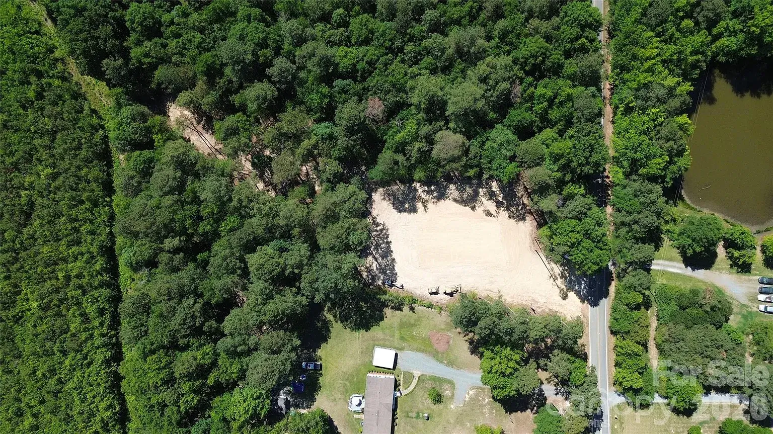 Overhead aerial view of a cleared homesite on a wooded 2-acre lot in Monroe, North Carolina, showing road frontage and surrounding mature trees.