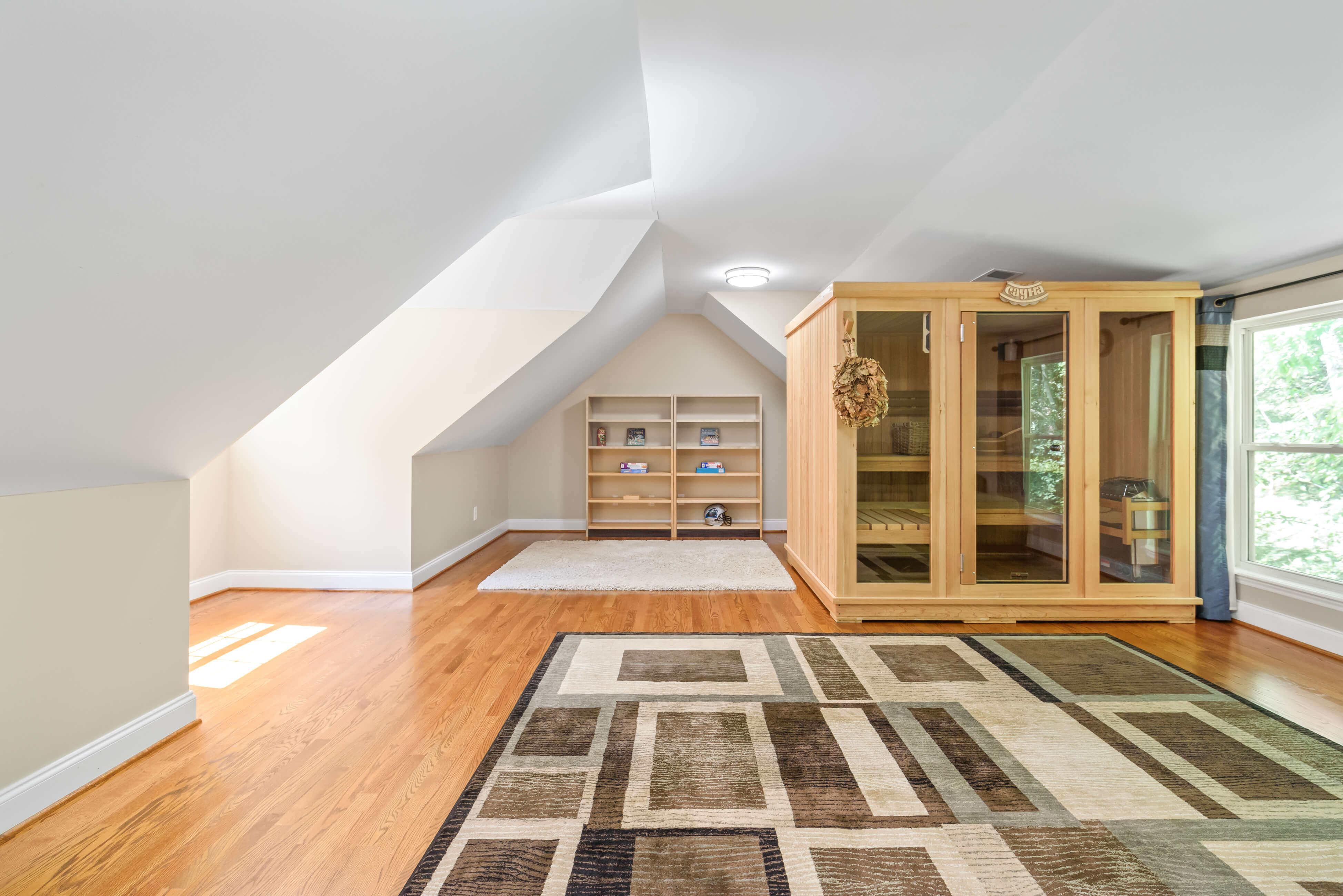 Finished bonus room with sloped ceilings, hardwood floor, shelves, area rug, and wood sauna