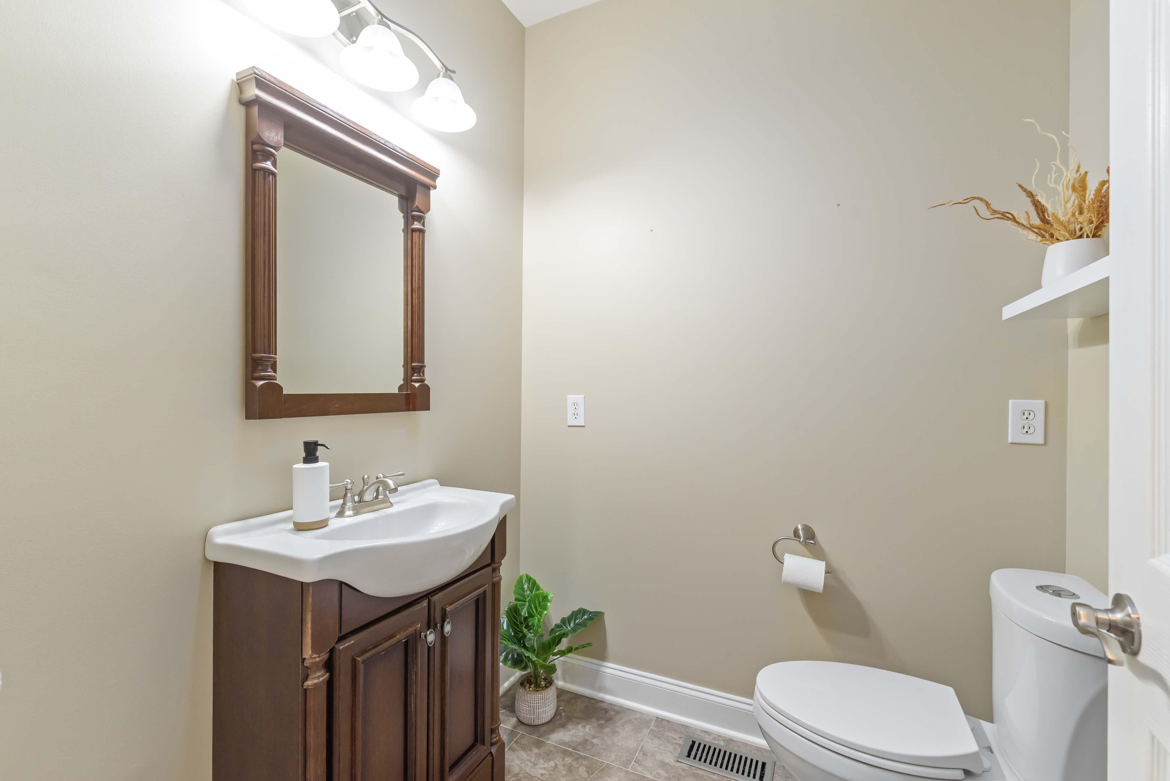 Half bath with vanity sink, framed mirror, toilet, and neutral walls