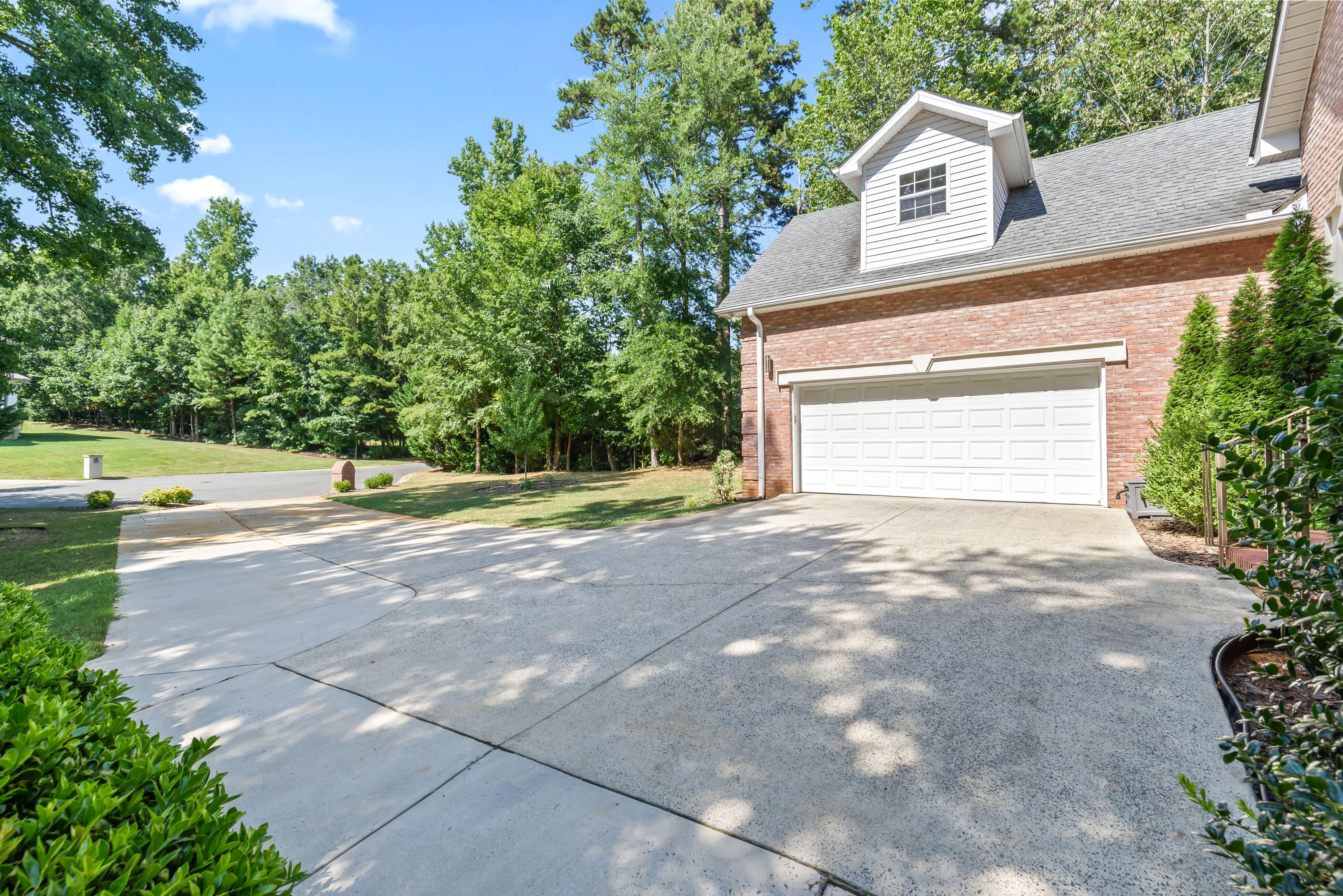Wide driveway in front of two-car garage with view toward tree-lined street