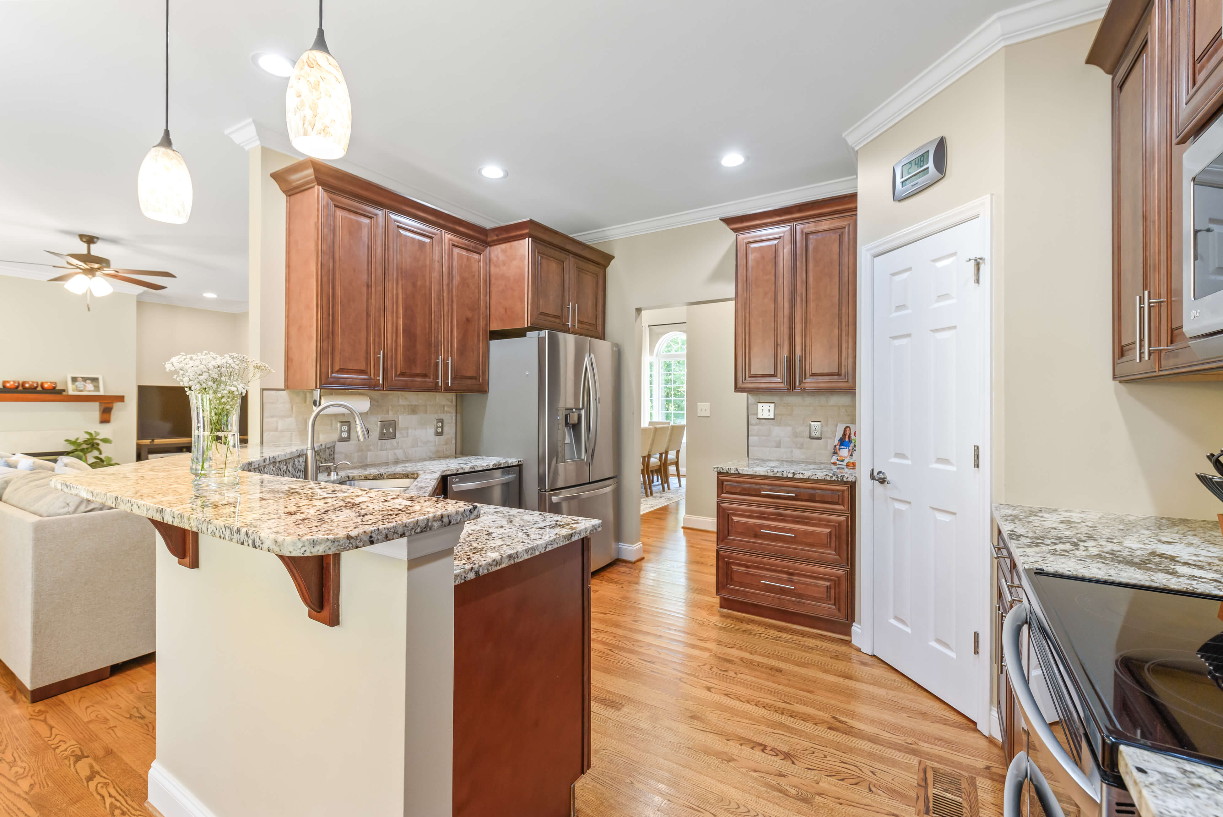 Kitchen view toward sink peninsula and stainless refrigerator, granite counters, and crown molding