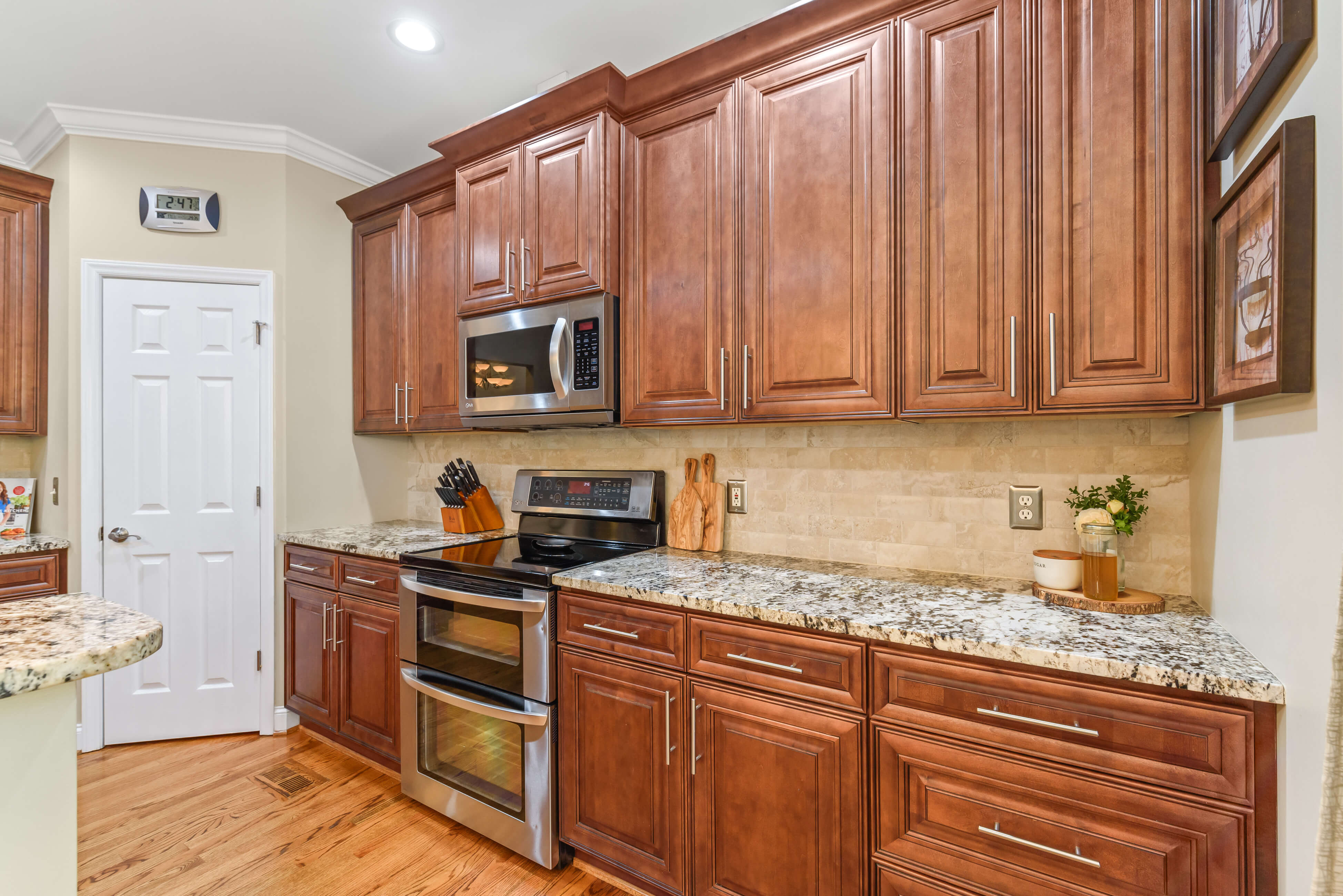 Kitchen range wall with double oven, microwave, granite counters, and raised‑panel cabinets