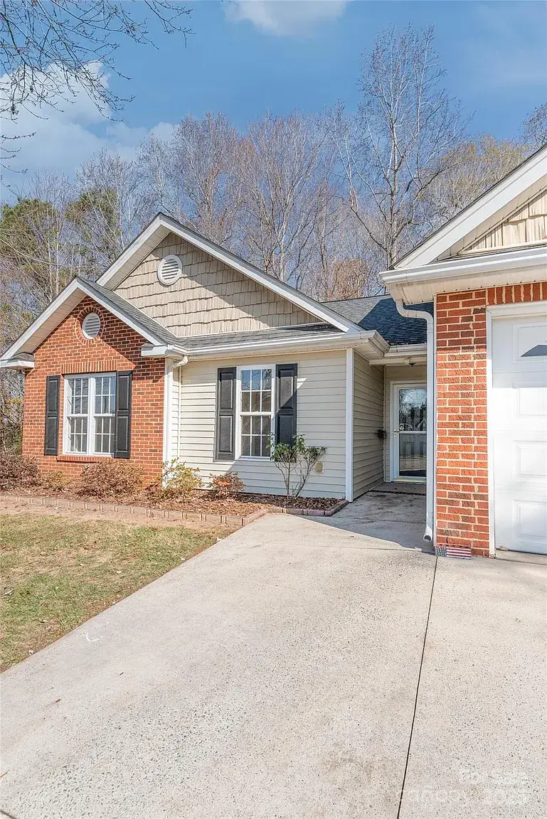 Front entry and driveway view of single-story home with brick and siding exterior in Mount Holly, North Carolina.